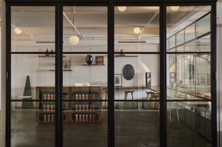 A glass-box-like design showroom filled with industrial modern furniture.