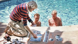 British painter, draughtsman, printmaker, stage designer and photographer David Hockney, poolside in Los Angeles, with polaroids of David Stoltz & Ian Falconer, circa 1978. (Photo by Michael Childers/Corbis via Getty Images)