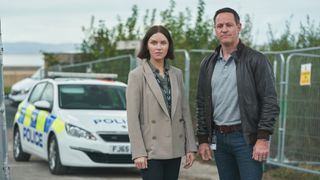 DS Karen Hobson (Erin Shanagher) and DS James Clarke (Andrew Dowbiggin) stood in front a police car