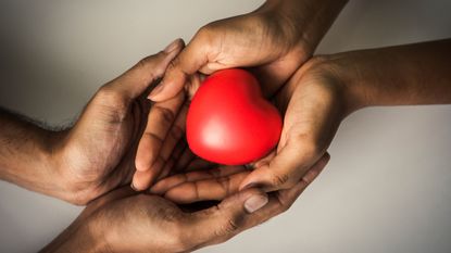 A pair of hands cradle a red heart knickknack.