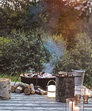 Outdoor fireplace ideas with traditional fire pit and wooden stools on rustic decking.