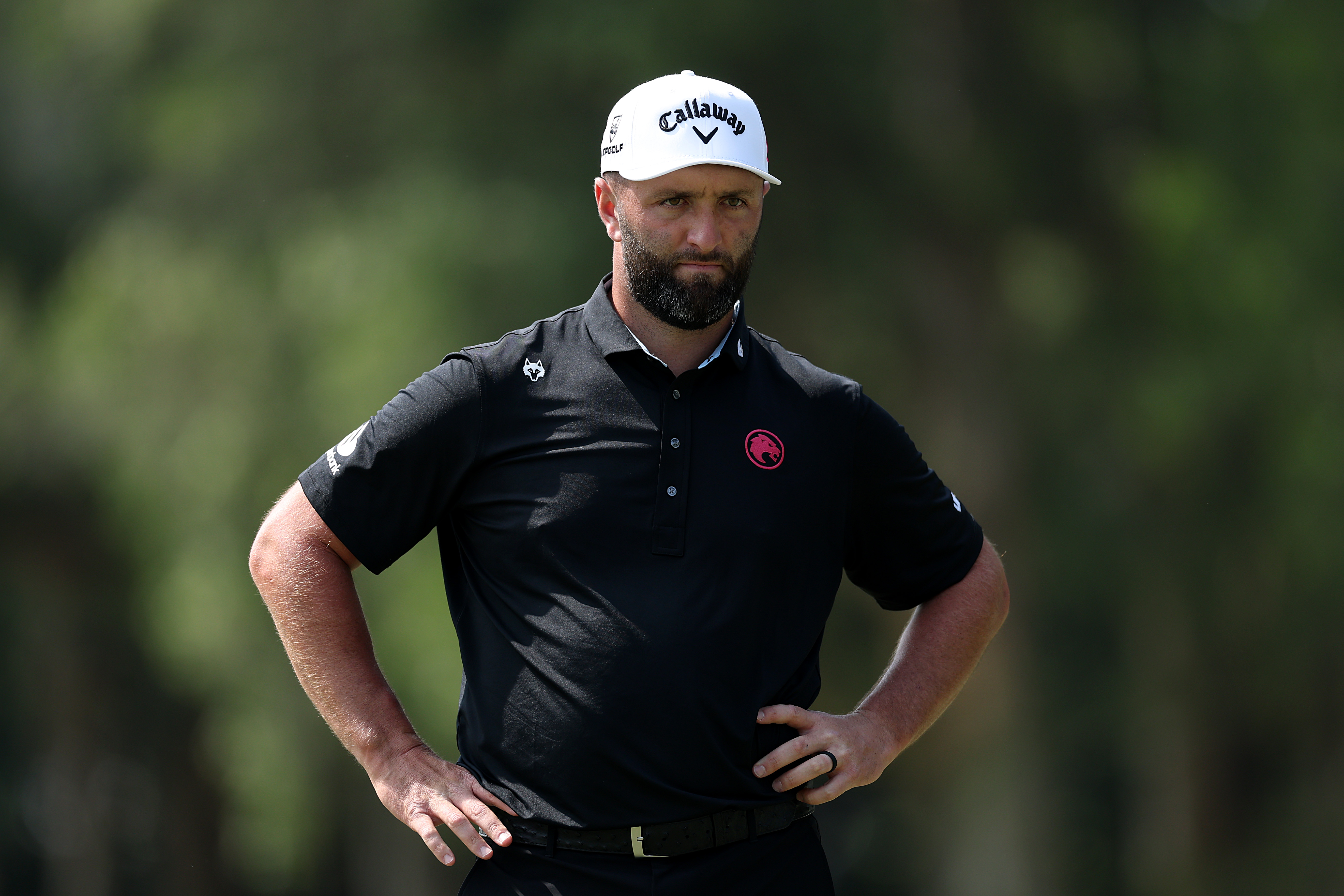 Jon Rahm waits with his hand on his hips