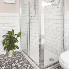 a white shower tray next to a tiled bathroom floor