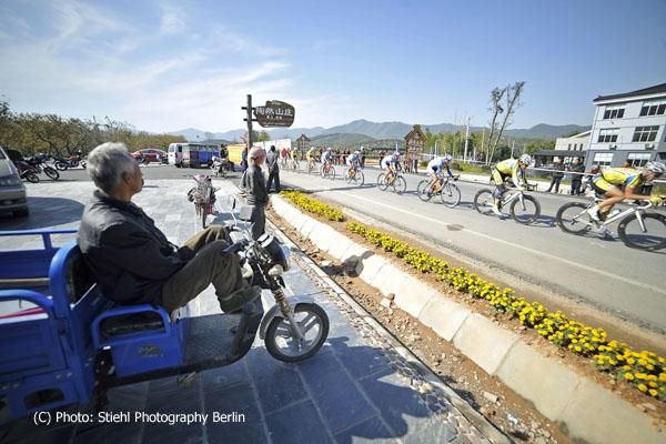 Locals watch the bunch speed passed along the Bamboo Forest circuit