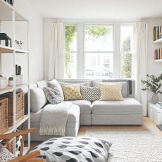 A corner modular sofa in light grey in a narrow bright, light living room