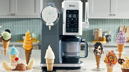 A Ninja&reg; CREAMi&reg; Scoop & Swirl on a kitchen counter surrounded by swirled ice cream in cones. 