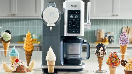 A Ninja&reg; CREAMi&reg; Scoop & Swirl on a kitchen counter surrounded by swirled ice cream in cones. 