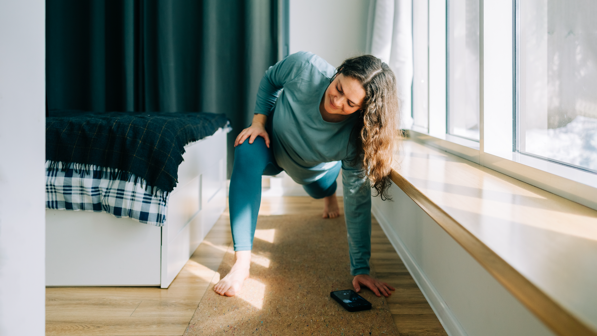 Woman doing mat Pilates in bedroom