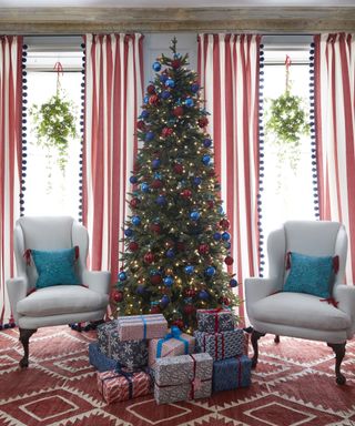 Christmas window decor ideas with a Christmas tree, double windows with wreaths in each, and red and blue decor