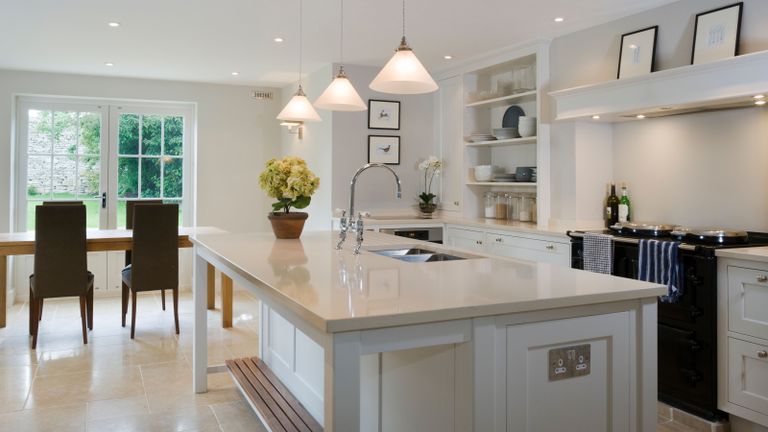 Large island unit in a bright light kitchen with dining area beyond