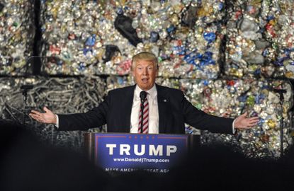 Donald Trump gives a speech in front of a wall of garbage.
