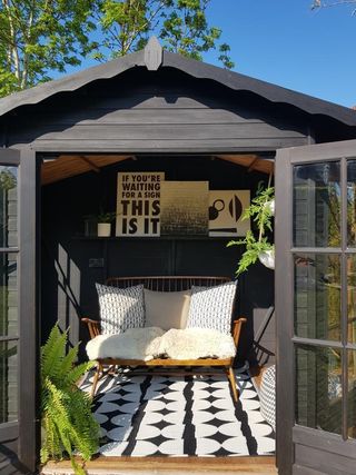 a shed painted in black with a sofa and art prints