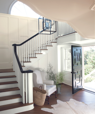 An entryway with an open front door and a large staircase.