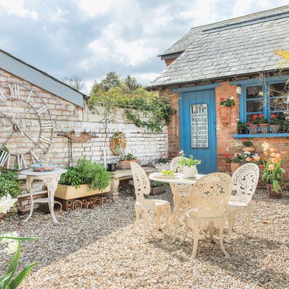gravel garden with cream bistro set and plants growing in various upcycled containers