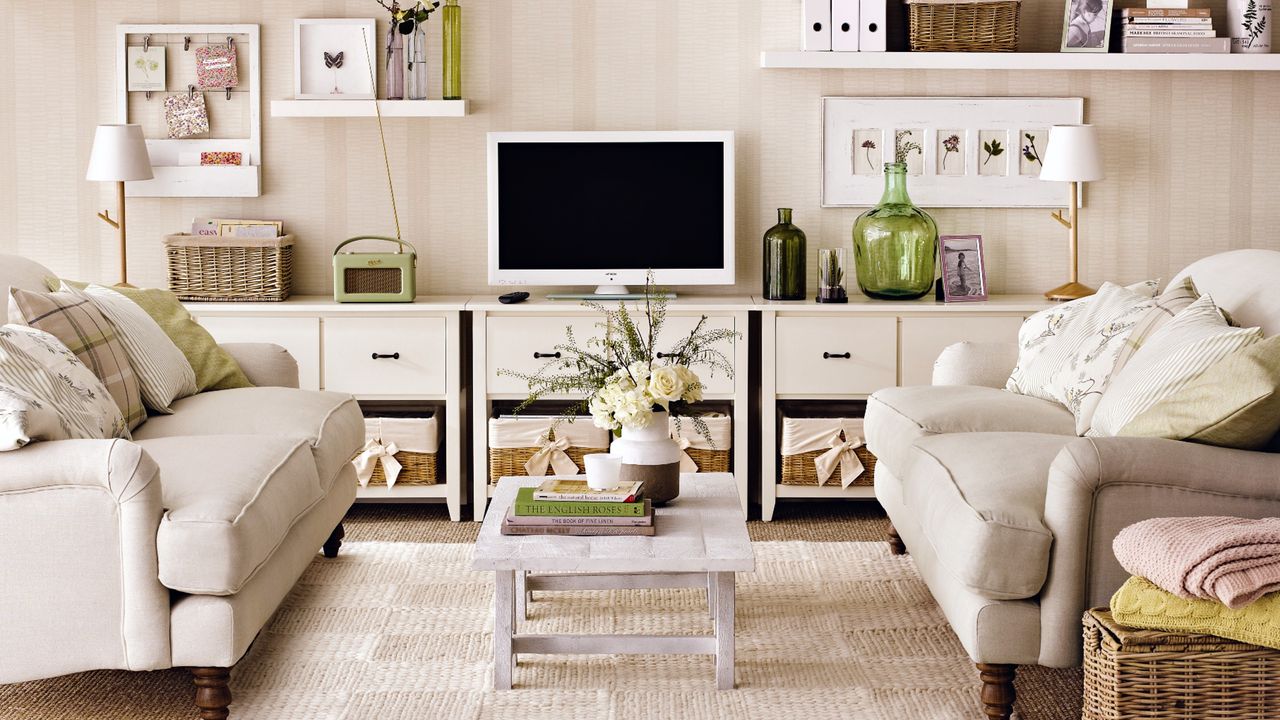 Two face-to-face cream sofas in living room, coffee table, TV console