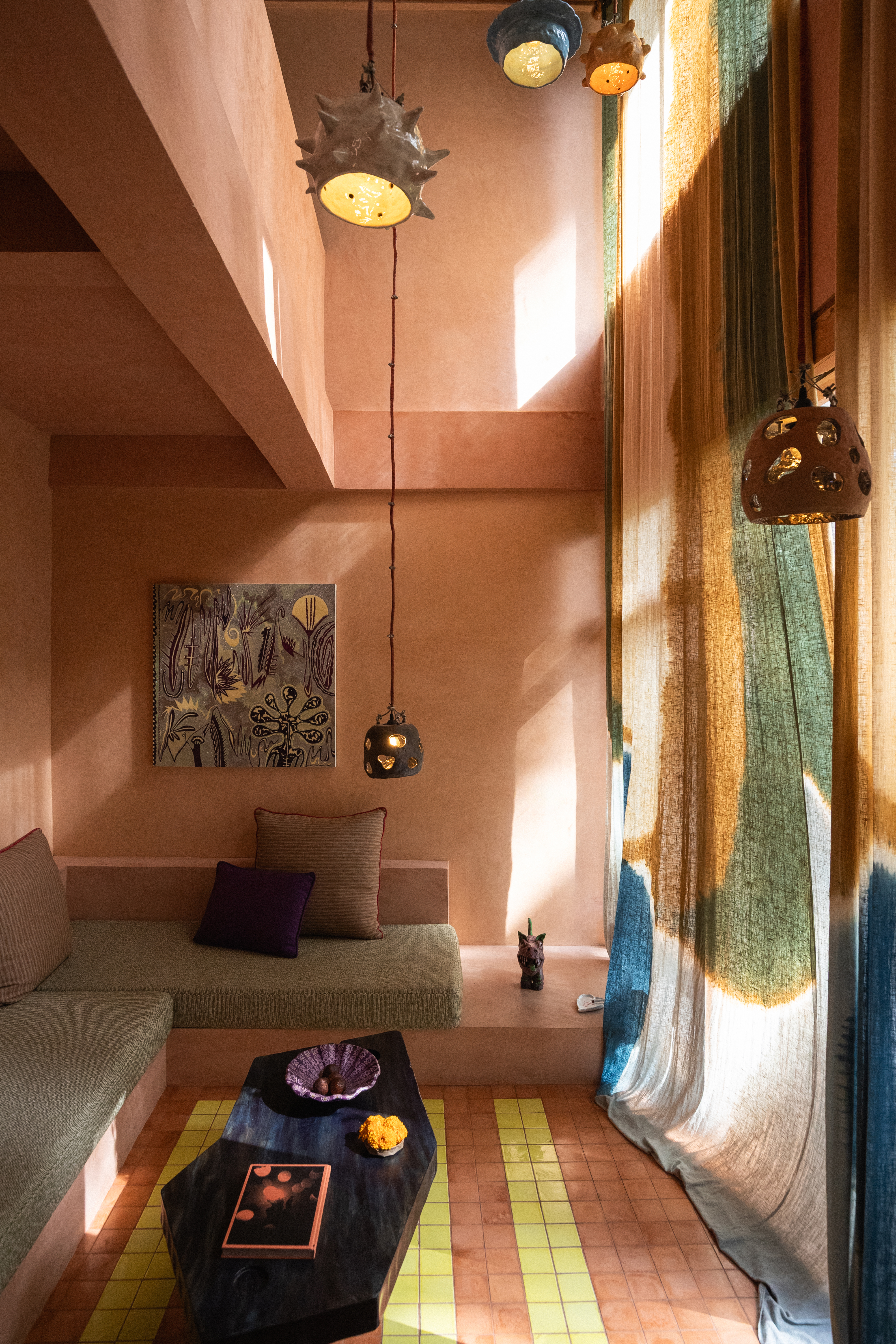 Interiors of a tropical interiors with curved passageways, terracotta walls, colorful curtains, woody furniture, color pops, and nature all around.