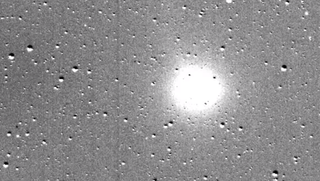 A still from a video released by NASA shows a comet passing a field of stars.