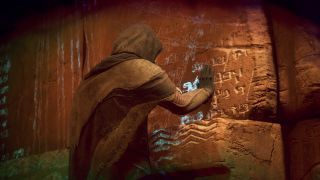 Dune: Awakening carbon ore locations - A character wearing Fremen-style clothing placing their hands on an inscribed rock wall.