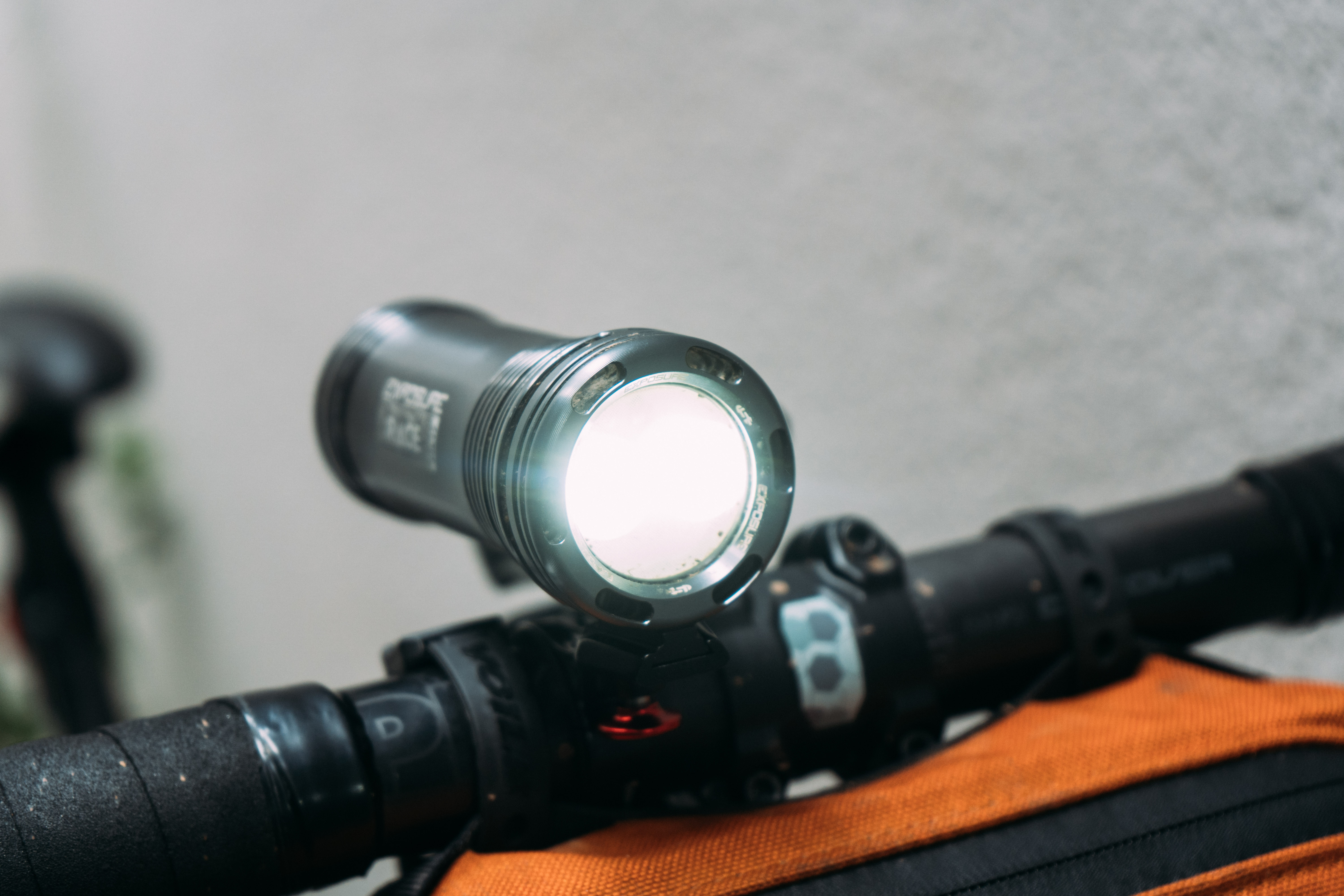 A grey bike light, swithced on, shows the high brightness of the twin bulbs