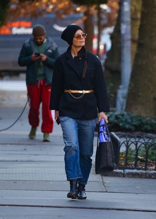 Katie Holmes walks down the street in Soho wearing a blue jacket with a gold belt and jeans