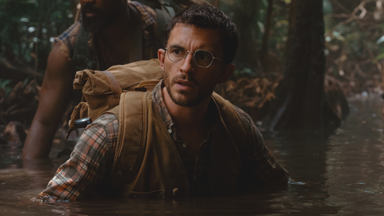 Jonathan Bailey wades through water with a look of worry in Jurassic World Rebirth. 
