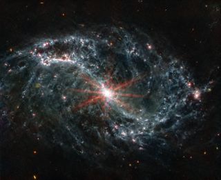 A wispy spiral galaxy looks like smoke in this JWST image