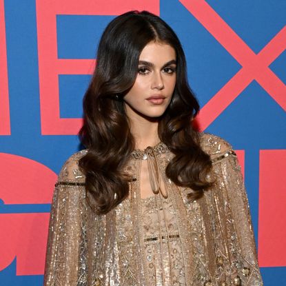 Kaia Gerber wears a glittery Valentino dress with a matching cape and knee socks