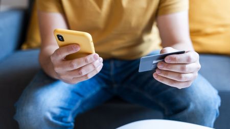Close-up of male hands holding a credit card and a mobile phone for an online transaction