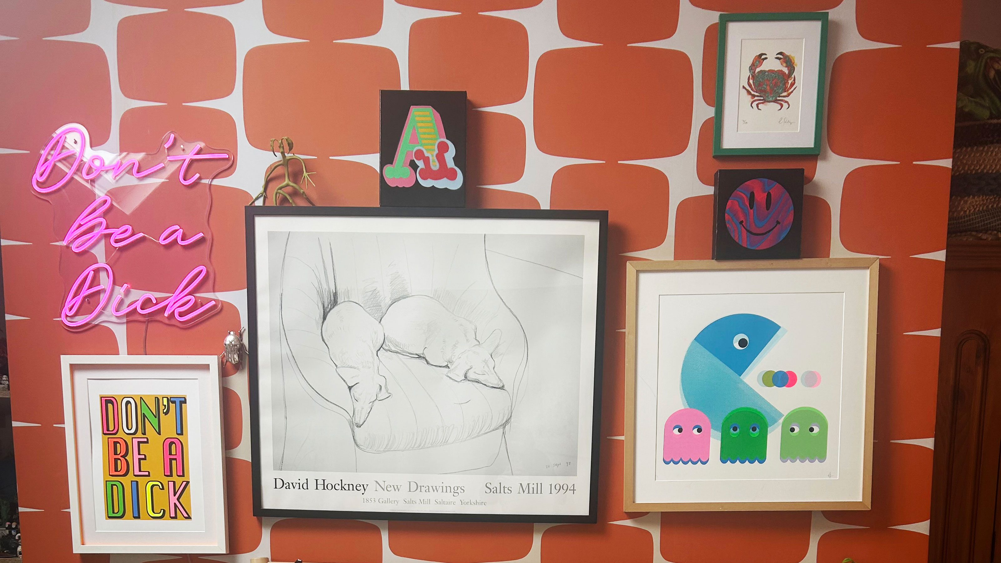 Orange patterned wallpaper covered with artwork and neon sign