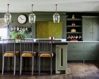 Green painted kitchen with green painted cabinets, kicthen island with bar stools and chartreuse feature tiles