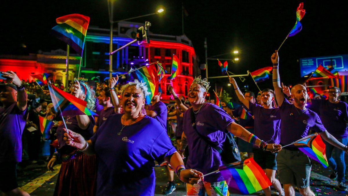 Participants waving rainbow flags march in the Sydney Mardi Gras Parade 2024.