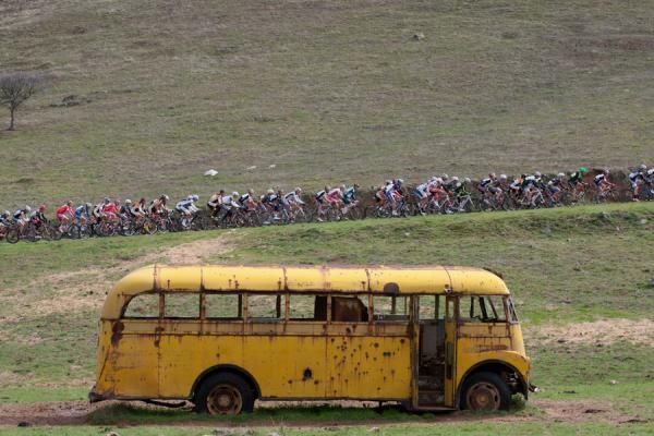 The peloton climbs past an abandoned bus on Haul Road.