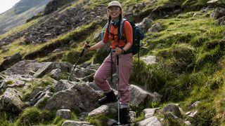 A woman stands on a rocky mountainside, holding a pair of Black Diamond Pursuit Trekking Poles