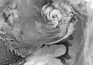 An Arctic hurricane (or polar low) northeast of Scandinavia, with a characteristic eye and counter-clockwise swirl of clouds. They grey area in the upper left-hand corner is sea ice.