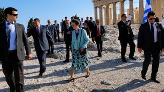 Princess Anne, Princess Royal walks atop the Acropolis surrounded by security officers
