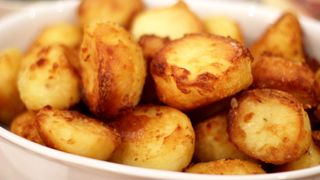 White dish served with golden roast potatoes piled high on top of each other