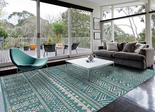 Bright teal patterned rug with coffee table central to lounging space with glass room