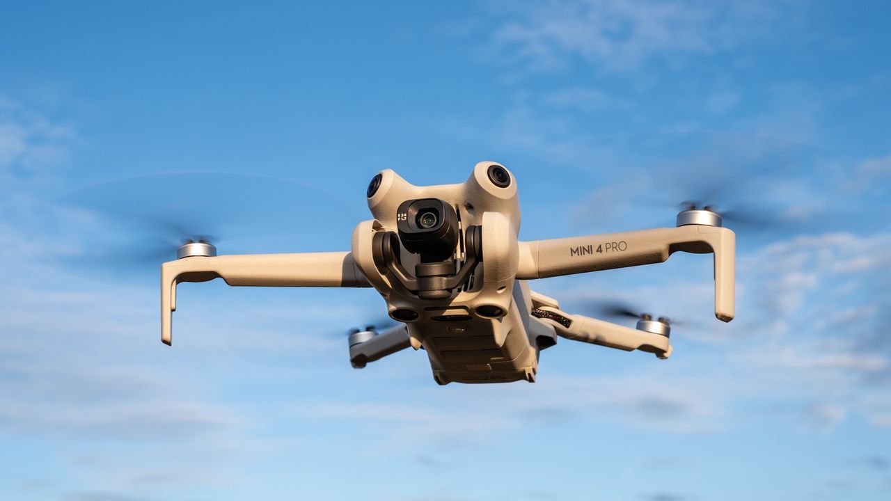 DJI Mini 4 Pro in flight with a blue sky behind