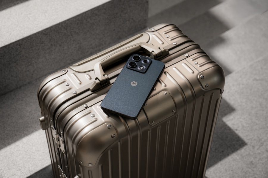 The Motorola Edge 70 Max in Dark Shadow sitting on top of a suitcase.