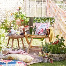 garden with wooden chair and cane stool cutions grass and potted plants