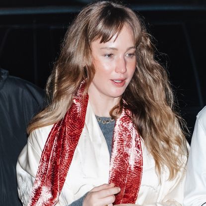 Jennifer Lawrence wore a velvet scarf, a white coat, jeans, and furry flip-flops to a concert in NYC