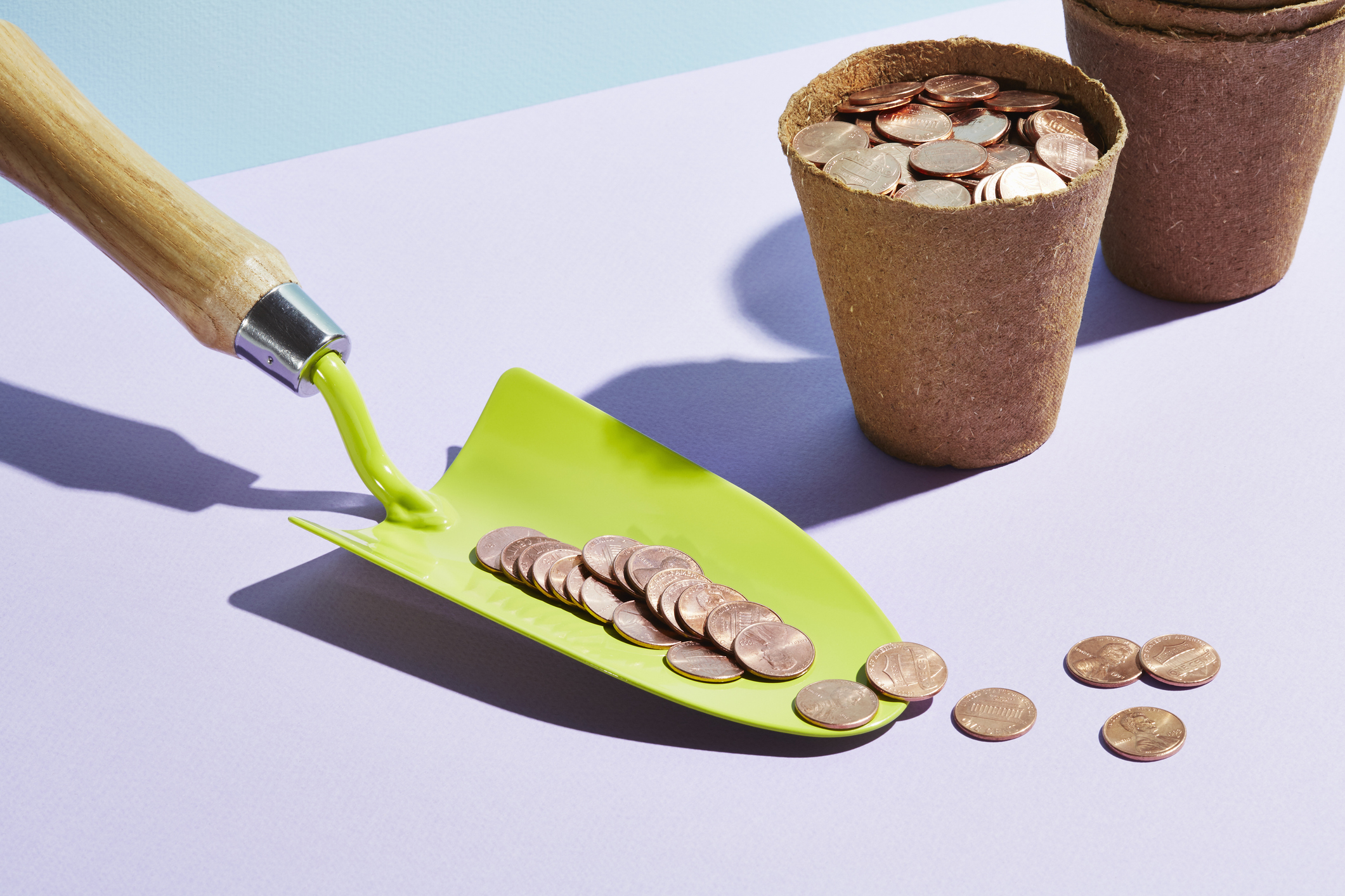 a gardeners trowel with coins sits next to a flower pot full of coins