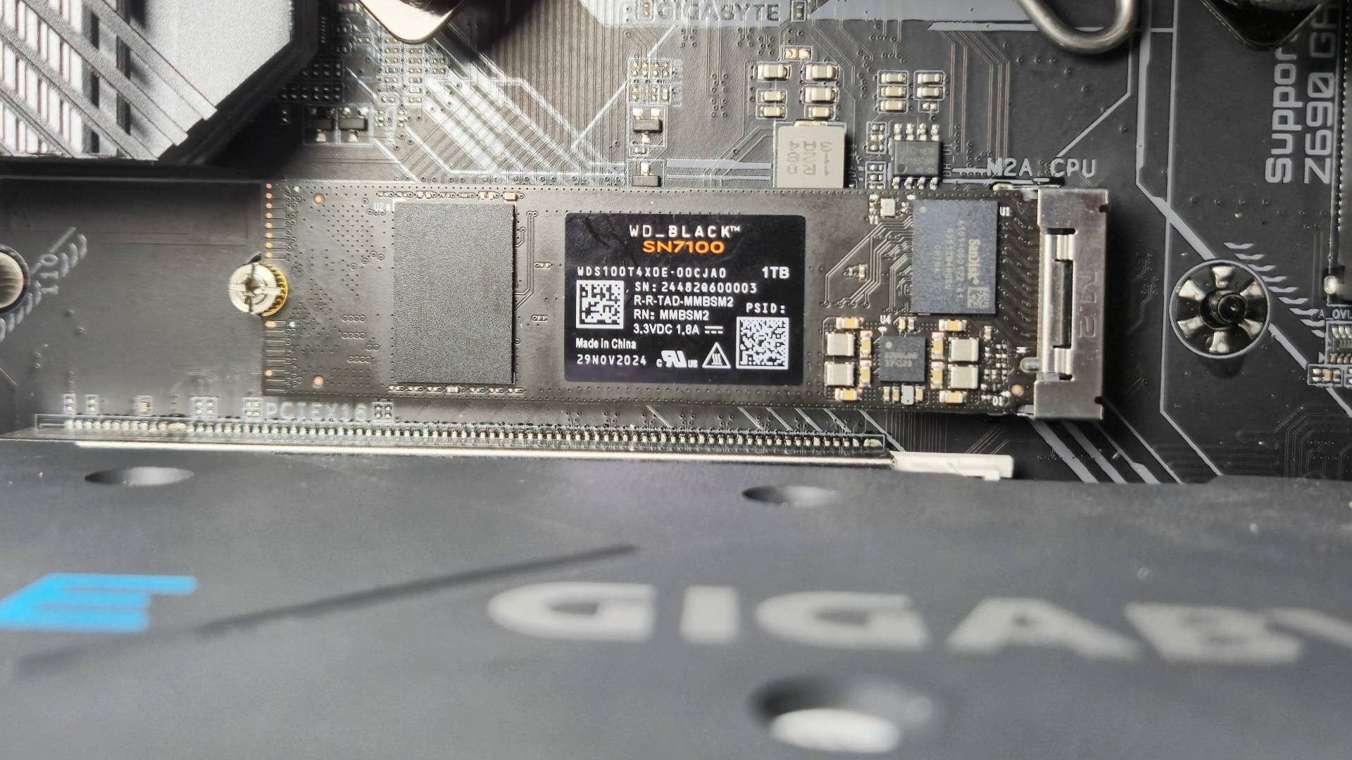 Photo of the inside of a PC rig showing the SN7100 SSD attached into the drive slot.
