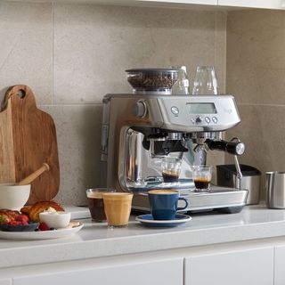 Sage coffee maker on a kitchen worktop with coffee cups and breakfast foods