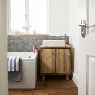 bathroom with white walls and grey tiles.