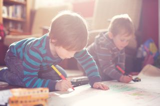 Two young boys drawing together