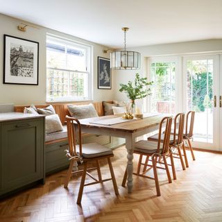 banquette seating with underneath storage flanked by green cabinetry and farmhouse table and chairs