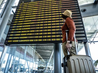 Woman In The Airport In Front Of The Flight Information Display