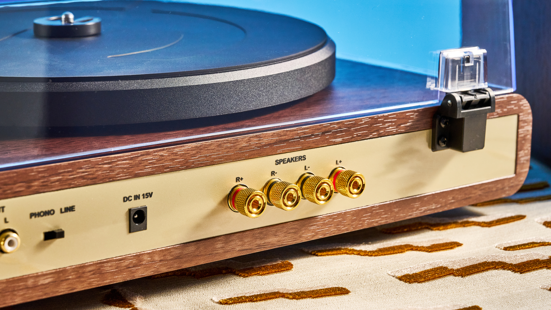 Crosley C65 turntable and bookshelf speakers photographed in front of a blue background on a brown table.