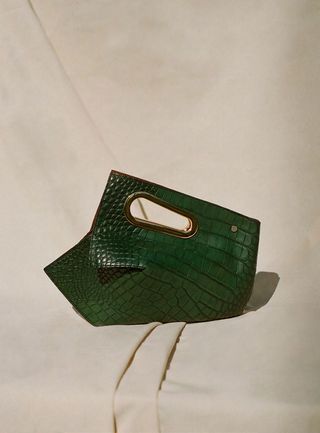 Green Croc Embossed bag with gold plated handles photographed on a cream cloth